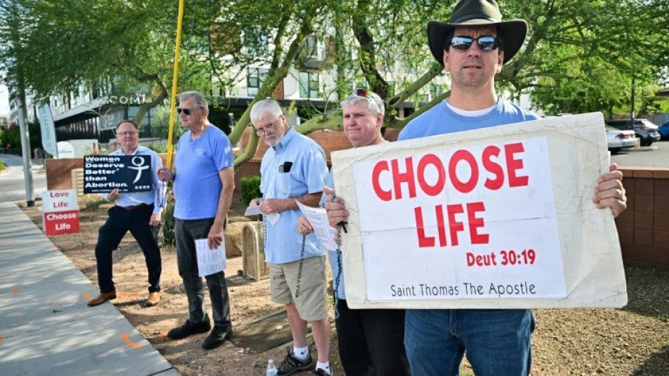 Matthew Engelthaler stands with a group of men from a local Catholic Church who gather "not to protest but to pray" for those arriving at Camelback Family Planning, an abortion clinic in Phoenix, Arizona 