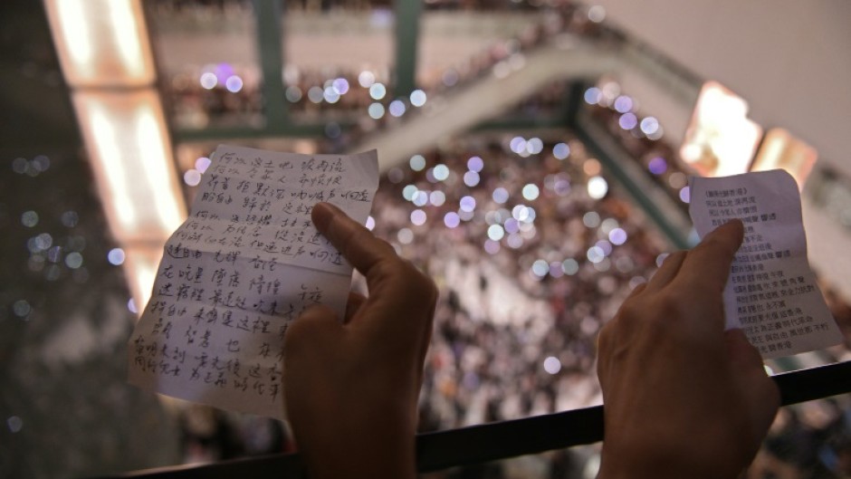 People hold the lyrics to 'Glory to Hong Kong’ at a shopping mall during the city's 2019 democracy protests
