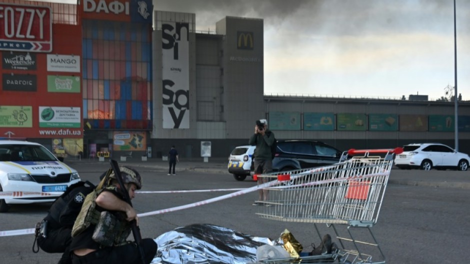 A police officer covers the body of a victim of the Russian strike on a hardware store in Kharkiv, Ukraine, on Saturday