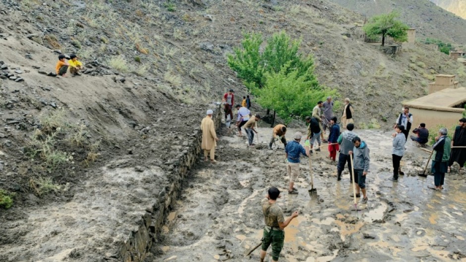 Afghan residents shovel mud following flash floods after heavy rainfall at Pesgaran village in Dara district, Panjshir province 