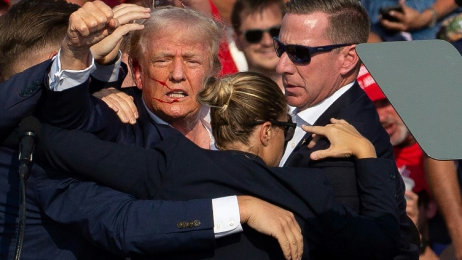 Republican US presidential candidate Donald Trump is surrounded by Secret Service agents as he is taken off the stage after an assassination attempt on July 13, 2024, at a rally in Pennsylvania