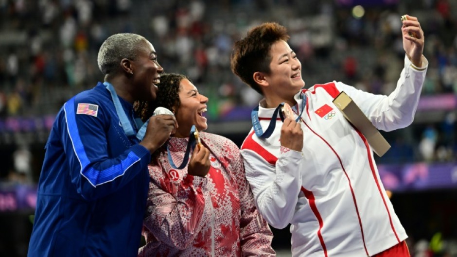 Winners of the women's hammer throw take a selfie with a Samsung flip phone 