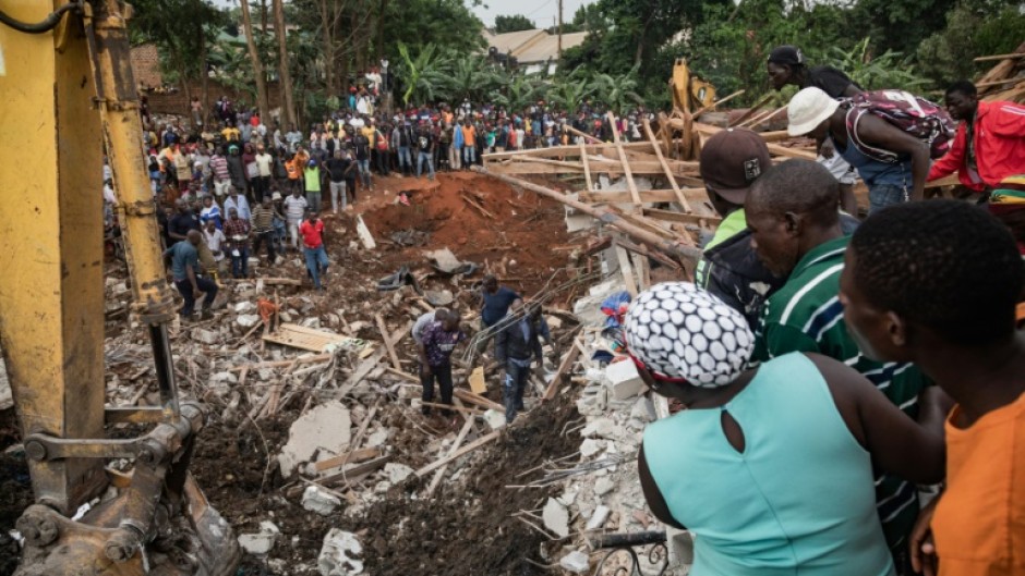 People looked on as an excavator helped  search for people trapped under the debris