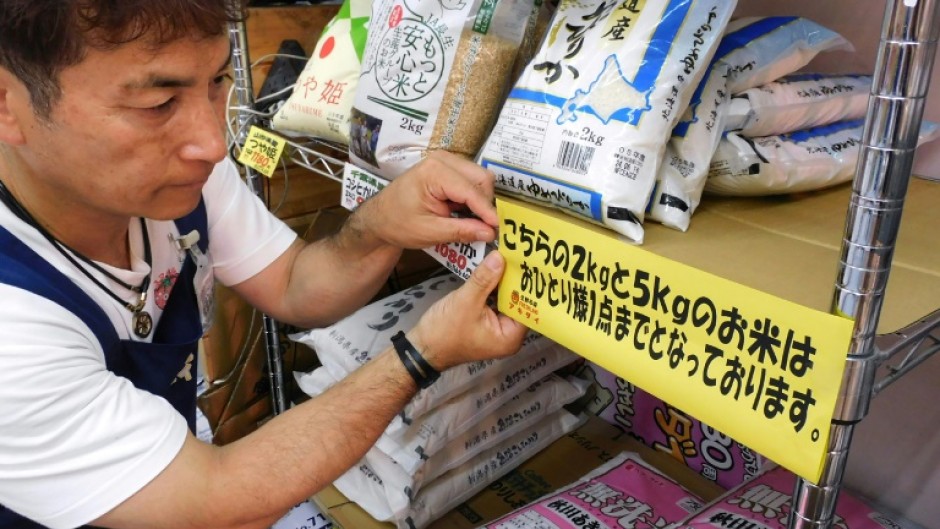 A supermarket worker puts up a sign telling customers they are restricted to one bag of rice each in Tokyo