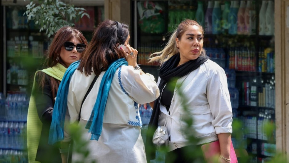 Women chat on a street in Tehran on the second anniversary of the protest movement