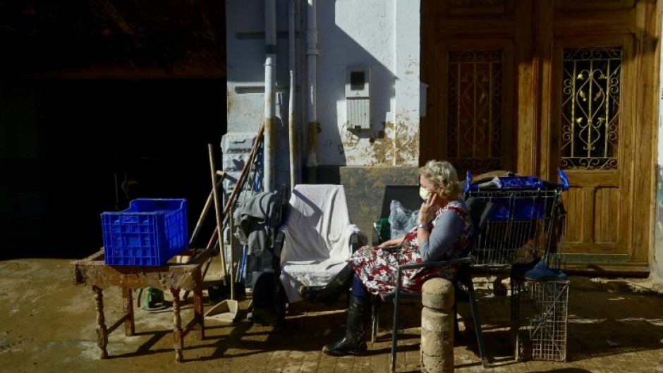 A woman rests in a street covered in mud in Paiporta, in the aftermath of deadly flooding in the region of Valencia