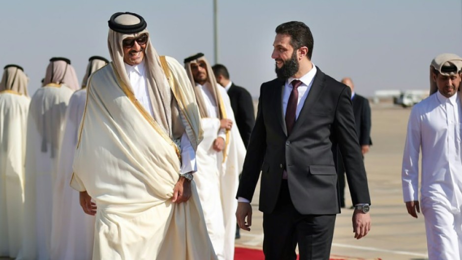 Qatar's Emir Sheikh Tamim bin Hamad Al-Thani (L) is welcomed by Syria's interim president Ahmed al-Sharaa in Damascus