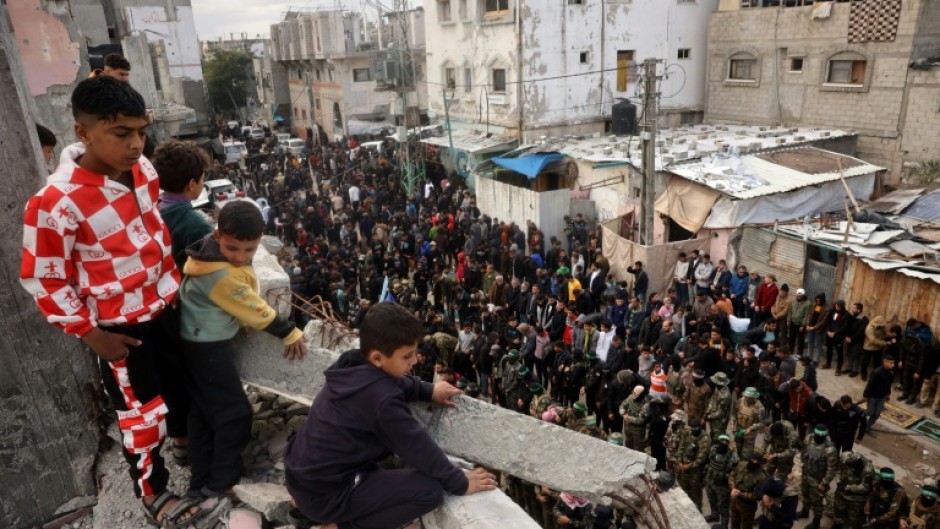 Children look on as Hamas fighters and mourners perform the noon prayer during the funeral for top Hamas commander Marwan Issa in central Gaza's Bureij refugee camp