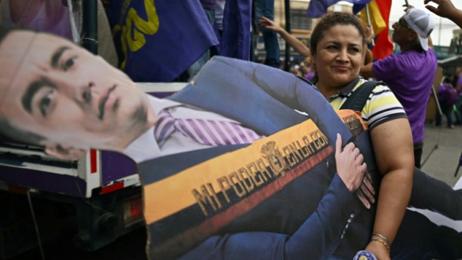 A supporter carries a life-size cardboard cutout of Ecuador's President and presidential candidate Daniel Noboa at a campaign rally