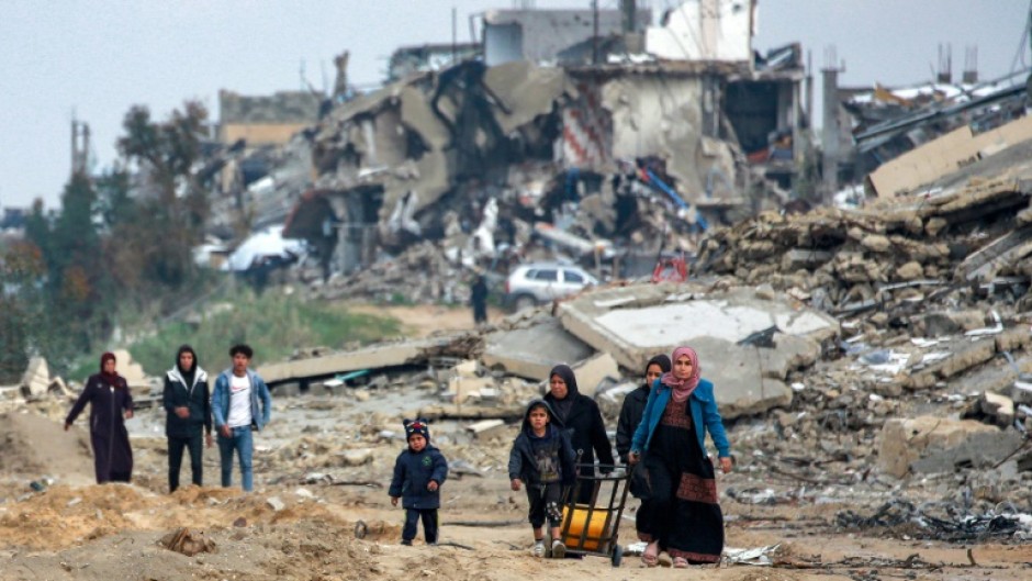 Palestinians walk along a destroyed road in Beit Lahia, in the war-ravaged north of the Gaza Strip