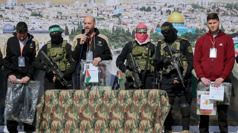 Hostages (L to R) Sagui Dekel-Chen, Yair Horn and Sasha Trupanov stand on stage next to Palestinian militants during their release