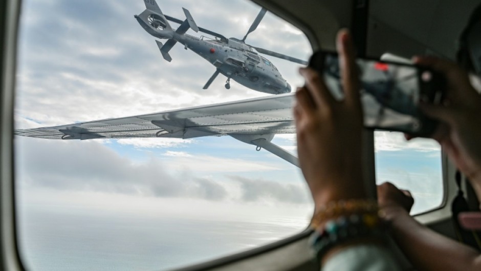 An aircraft identified by the Philippine Coast Guard as a Chinese Navy helicopter (L) flies near a plane carrying journalists over the contested Scarborough Shoal in the South China Sea