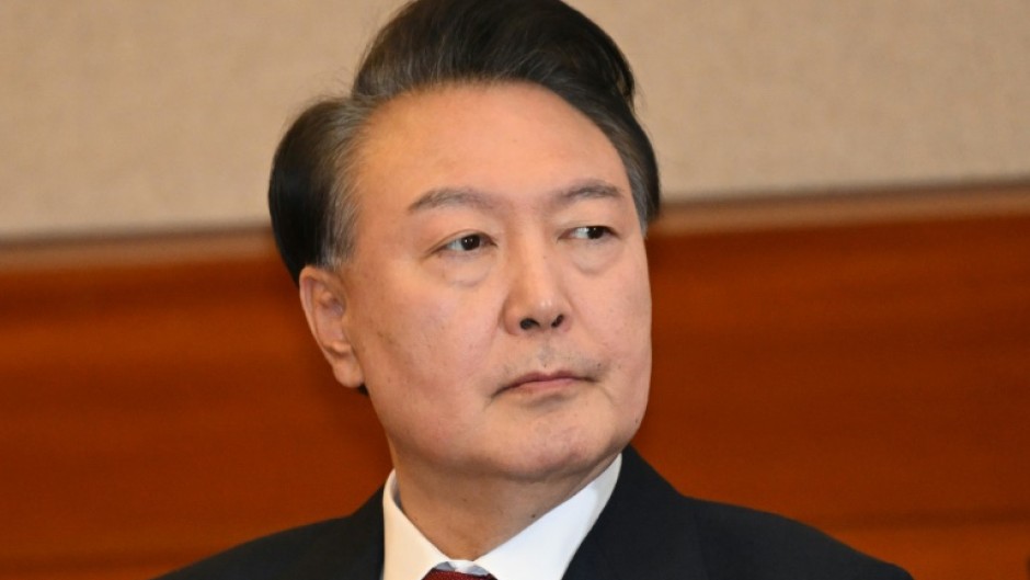 A defaced poster (L) of opposition Democratic Party leader Lee Jae-myung is displayed alongside supporters of South Korean leader Yoon Suk Yeol, during a rally near the Central District Court in Seoul on February 20, 2025