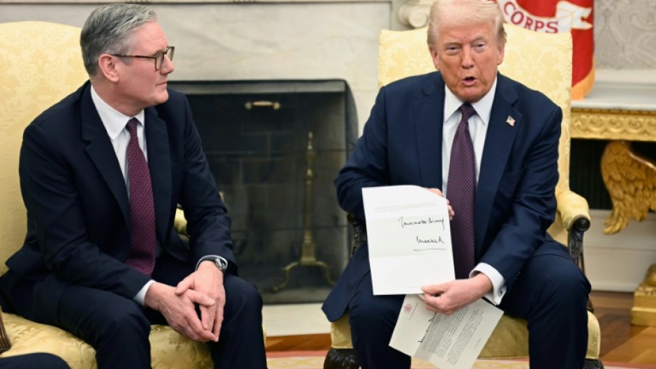 Donald Trump holds a letter from Britain's King Charles III during a bilateral meeting with British Prime Minister Keir Starmer in the Oval Office 