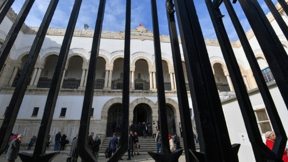 People stand in the yard of the Tunis Palace of Justice as the first hearing against detainees accused of involvement in a conspiracy case against state security starts
