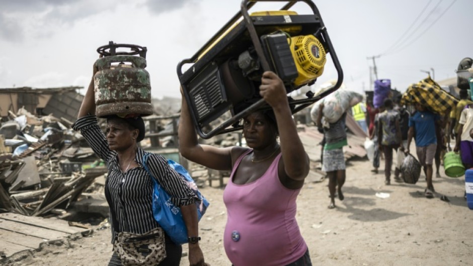 Residents carry their belongings as authorities demolish their homes in the working-class neighbourhood of Otumara, in Lagos, Nigeria