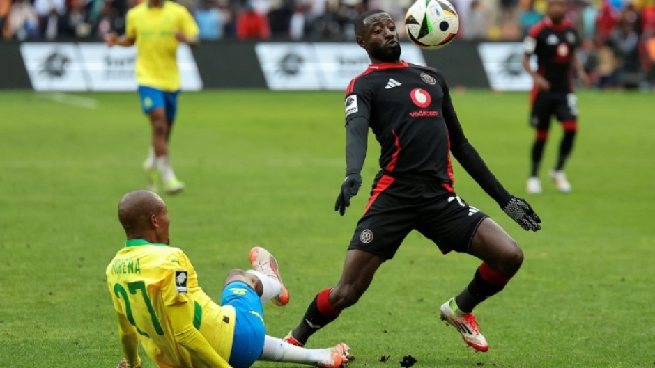 Deon Hotto (R) controls the ball watched by fallen Khuliso Mudau of Mamelodi Sundowns during a South African Premiership match in Johannesburg on March 16, 2025.
