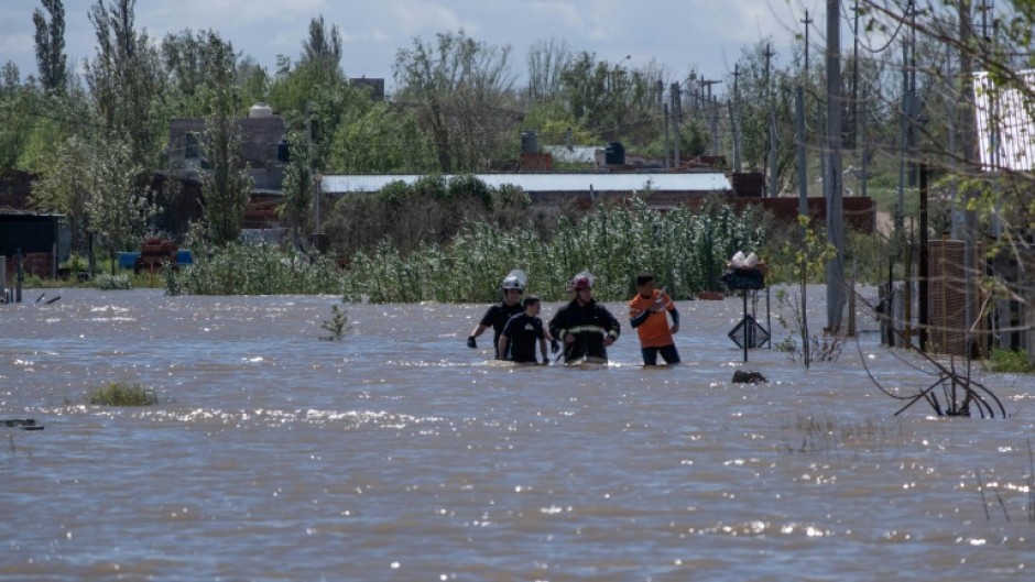 Rescuers wade through floodwaters following a heavy storm that hit the Argentinian port city of Bahia Blanca