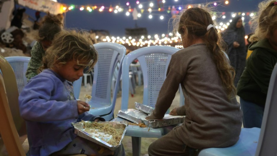 Palestinian children eat their food during a group Iftar meal, the evening meal with which Muslims end their daily fast at sunset, in Gaza City 