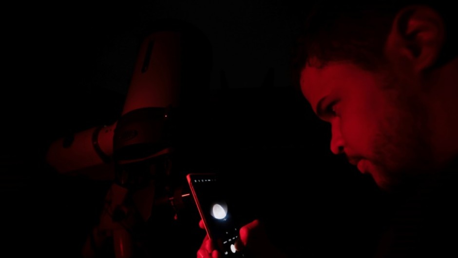 A man photographs the 'blood moon' with his phone through a telescope in Belo Horizonte, Brazil on March 14, 2025