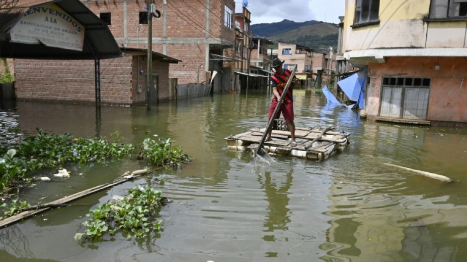 Rafael Quispe steers a makeshift raft through what used to be the streets of his village in western Bolivia