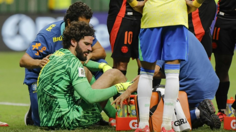 Alisson Becker receives treatment on the pitch after his collision with Colombia defender Davinson Sanchez
