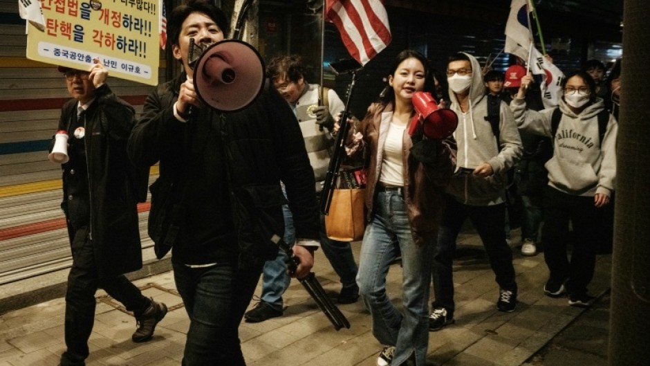 Supporters of impeached South Korean President Yoon Suk Yeol shout at protesters against him as they march past each other on a street