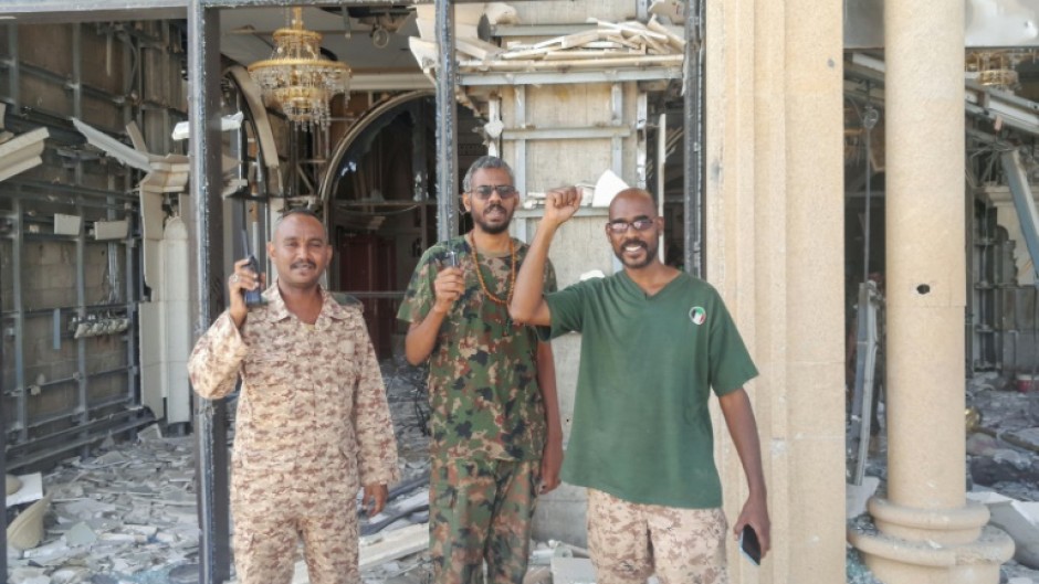Fighters loyal to Sudan's regular army pose for photographs at the battle-damaged presidential palace in Khartoum after its recapture from the paramilitary Rapid Support Forces