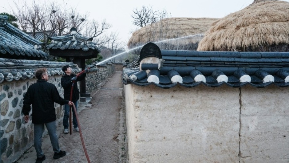 Firefighters are spraying water on thatched roofs in Hahoe Folk Village, which is UNESCO listed