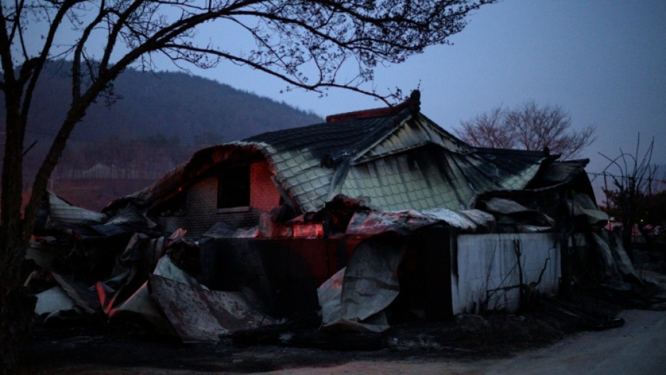 A house glows after being torched by a wildfire in Cheongsong