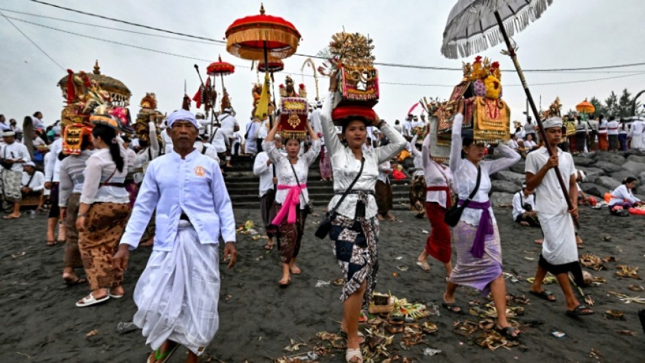 Hindu devotees take offerings to a beach near Denpasar