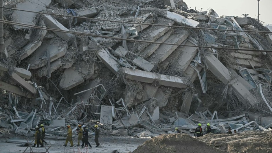 Rescue workers walk past debris at a construction site after a building collapsed in Bangkok following the earthquake