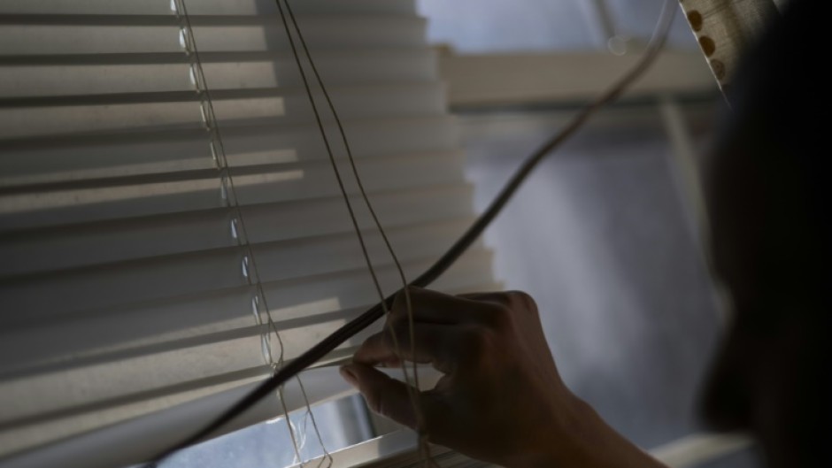 Rosario peers through her window blinds for any lurking US ICE agents outside her building