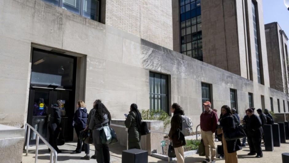 Federal workers wait in line to access to the Mary E. Switzer Memorial Building that houses the US Department of Health and Human Services in Washington, DC