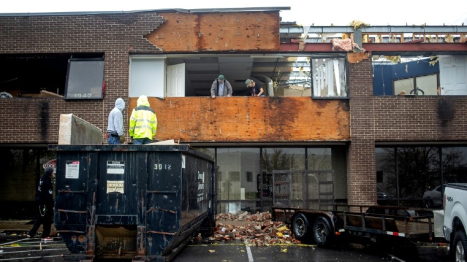 People remove debris from a building destroyed by a tornado in Louisville, Kentucky