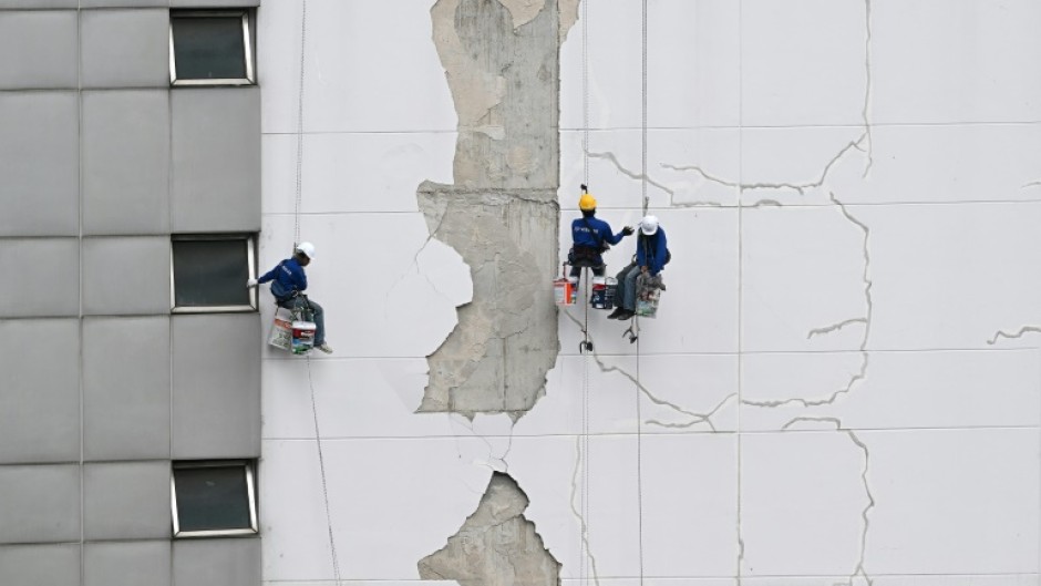 Workers repair damage on the exterior of a high-rise building in Bangkok following the March 28 earthquake