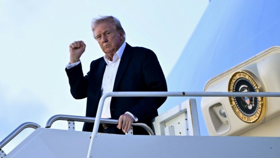 US President Donald Trump raises a fist as he steps off Air Force One at Palm Beach International Airport in Florida on April 11, 2025, while heading to spend the weekend at his Mar-a-Lago resort
