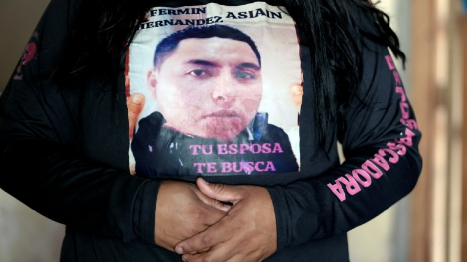 "Your wife is looking for you" reads a message worn by Rubi Cruz, whose husband is one of more than 120,000 people missing in Mexico