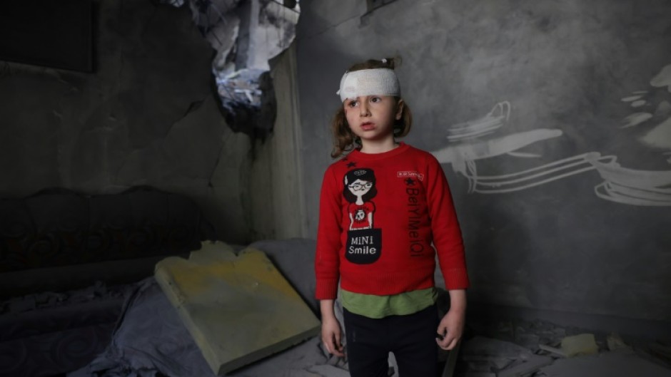 A wounded Palestinian girl stands amid the debris of her family home after overnight Israeli strikes