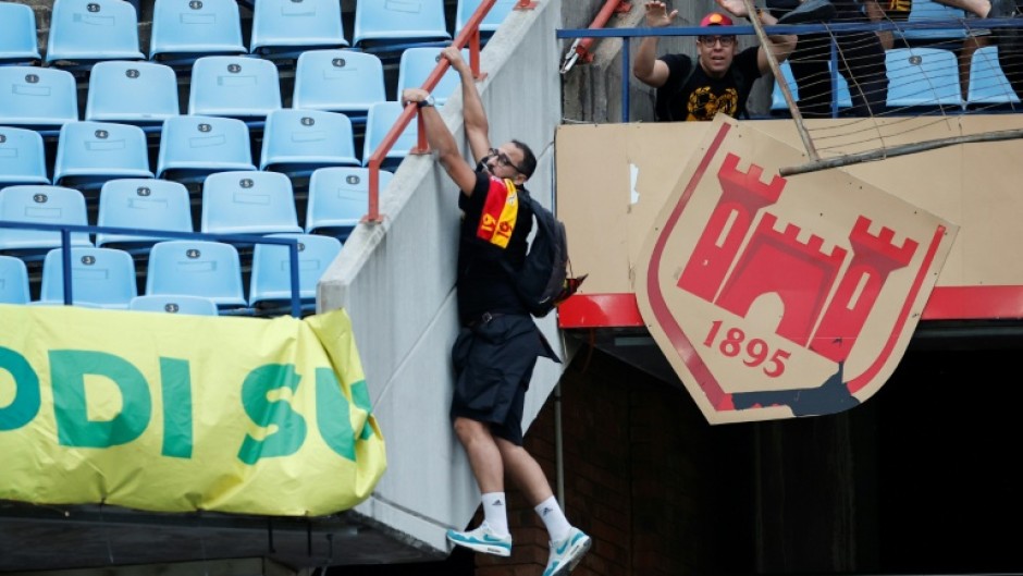 An Esperance supporter clings to a railing at a Pretoria stadium during crowd violence after a CAF Champions League match against Mamelodi Sundowns on April 1.