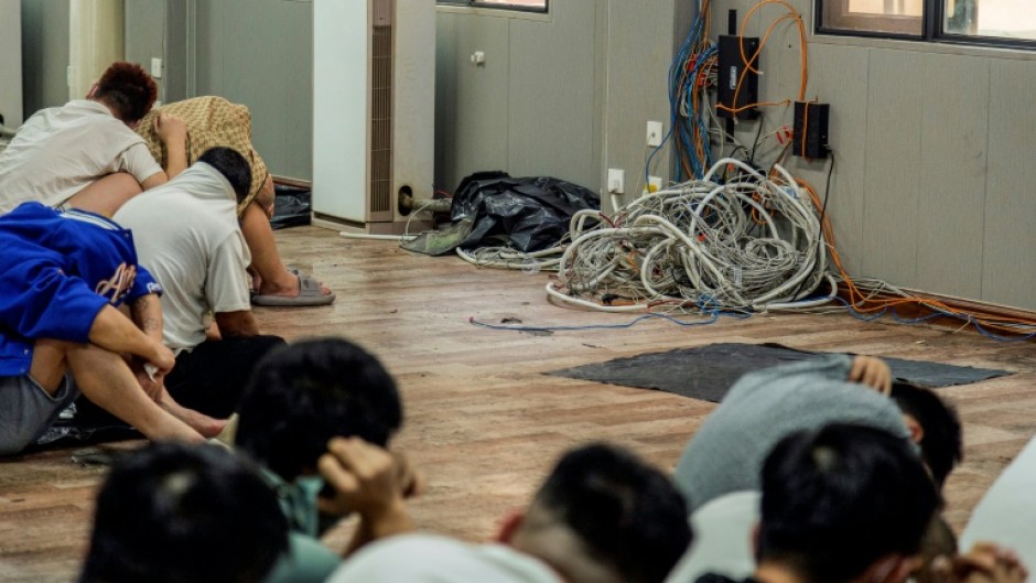 Alleged scam centre workers beside dismantled electronic appliances during a crackdown operation in Myanmar