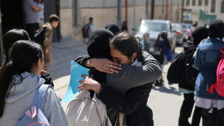 Palestinian schoolgirls embrace as they leave a UNWRA school