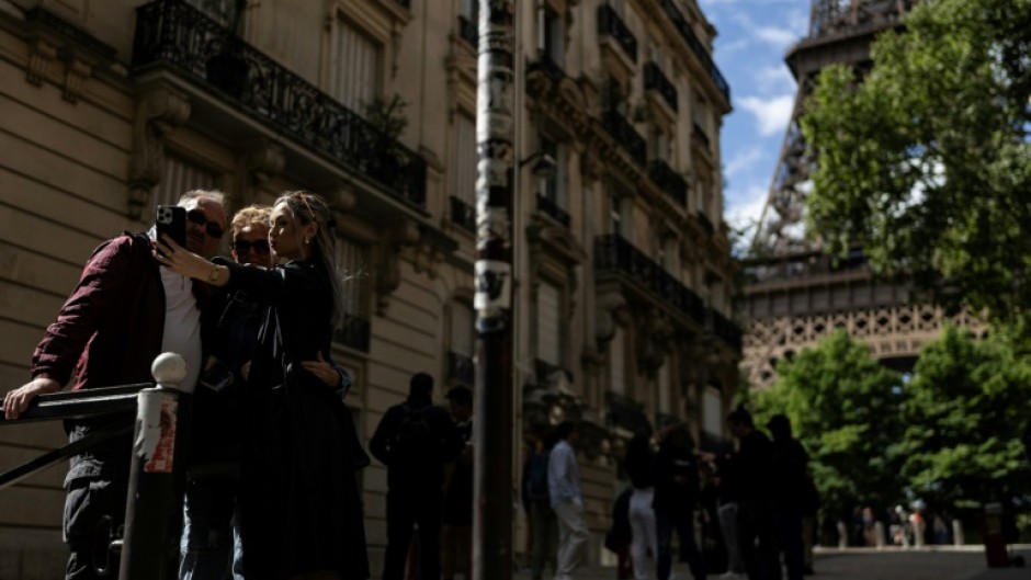 Three pedestrians take a selfie on the picturesque alleyway at the end of Rue de l'Universite, Paris