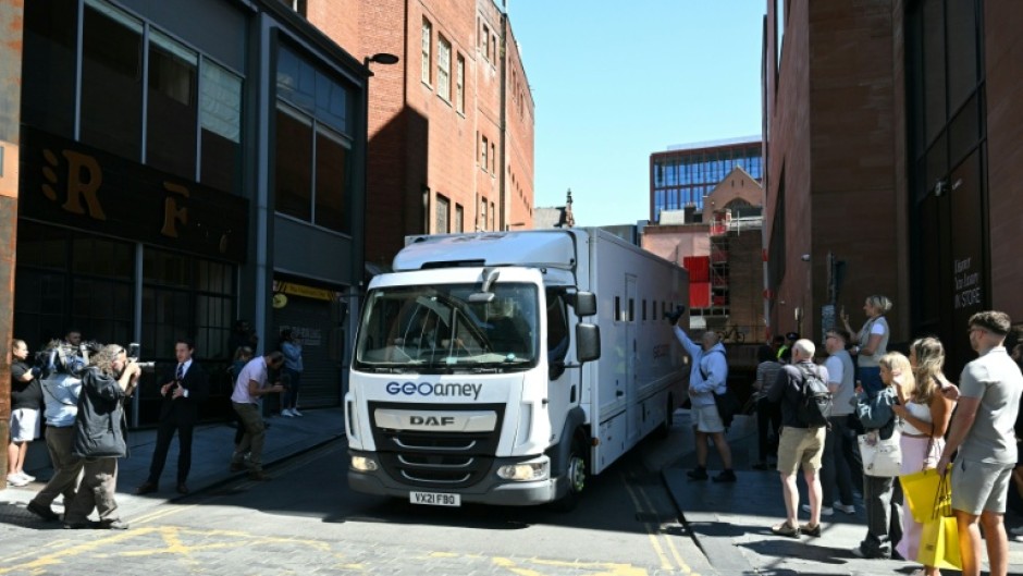 Members of the public and photographers look on as a prison van leaves from the back of a Manchester court shortly after US R&B singer Chris Brown charged with a 2023 assault in a London nightclub