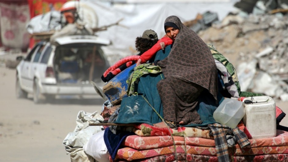 A Palestinian woman sits atop her family belongings as people flee Gaza City