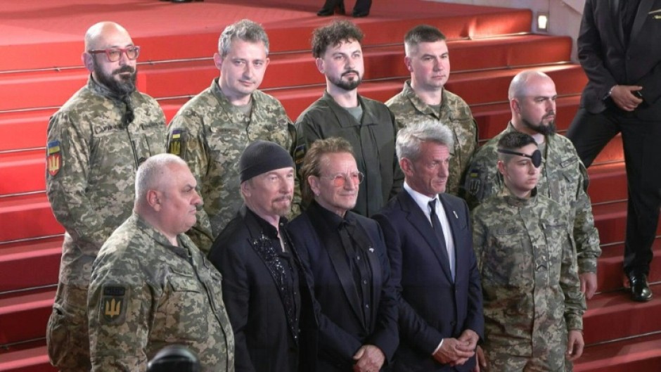 Bono, The Edge and US actor Sean Penn pose with Ukrainian soldiers on the Cannes red carpet