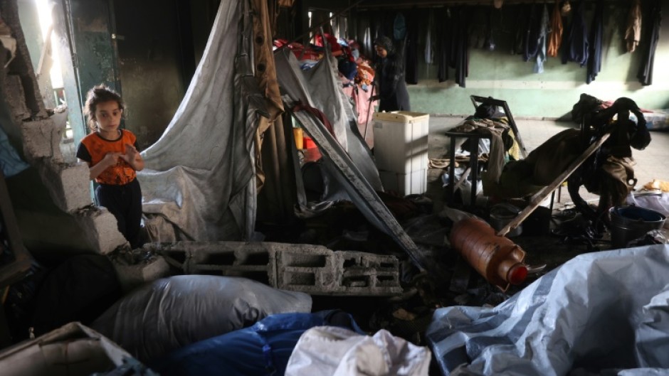 Palestinians look through the debris in a classroom after a strike hit a school serving as a shelter for displaced people