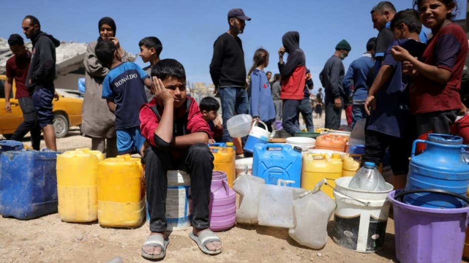 Palestinians attempt to collect water at a camp for displaced people in Gaza City