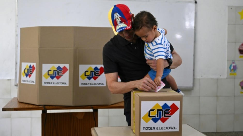 Venezuelan opposition candidate Henrique Capriles casts his vote while holding his son at a polling station in Caracas