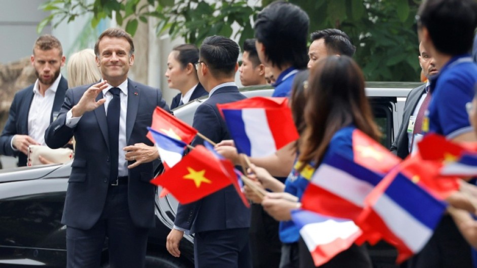 France's President Emmanuel Macron is greeted by flag waving university students in Hanoi